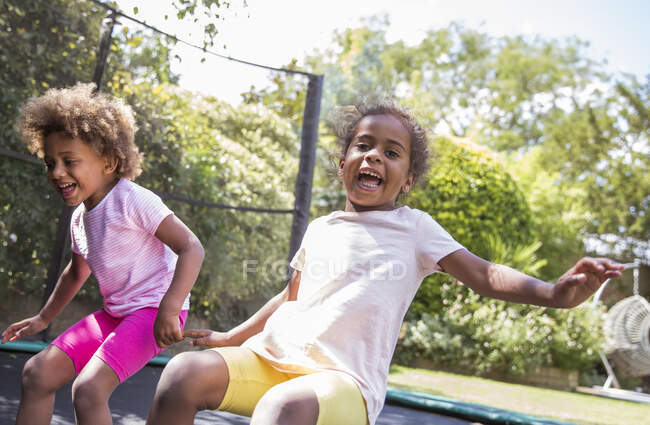 Portrait joyeuses sœurs ludiques sautant sur le trampoline arrière-cour — Photo de stock