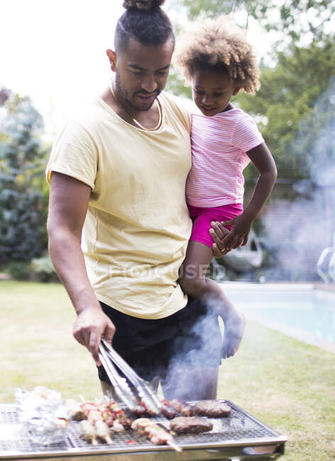 Father holding daughter at barbecue grill in summer backyard — Stock Photo