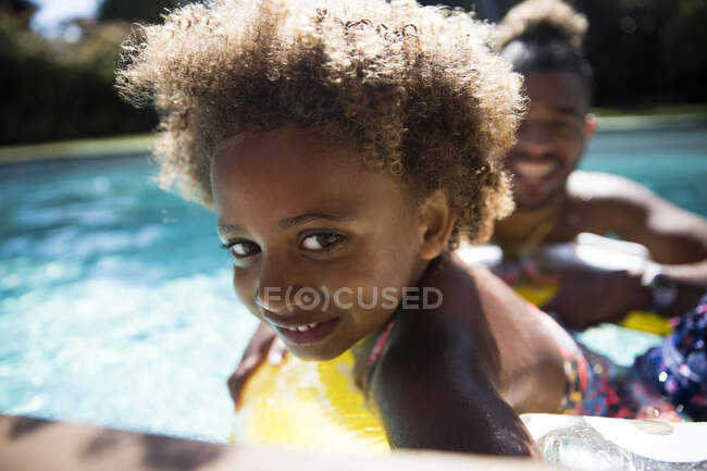 Portrait cute girl with curly hair in sunny summer swimming pool — Stock Photo