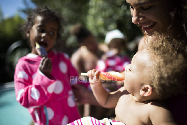 Glückliche Familie genießt Eis am Stiel am sonnigen Sommerpool — Stockfoto