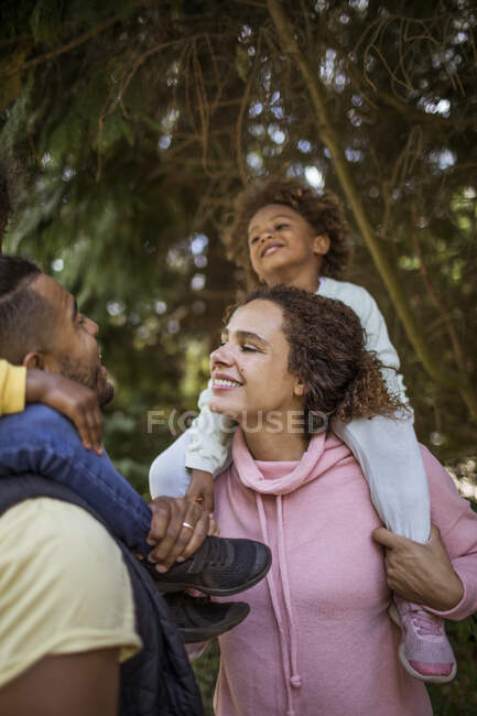 Família feliz abaixo de árvores no parque — Fotografia de Stock