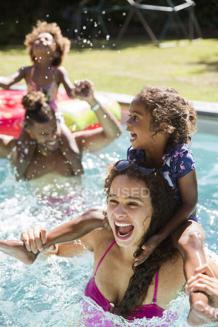 Felice famiglia giocosa nella soleggiata piscina estiva — Foto stock