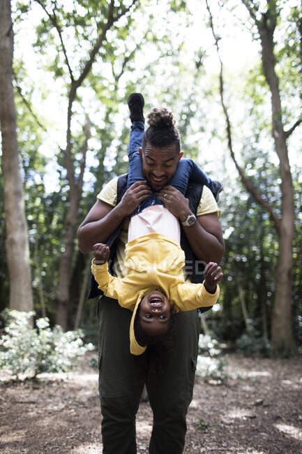Playful father holding daughter upside down on hike in woods — Stock Photo