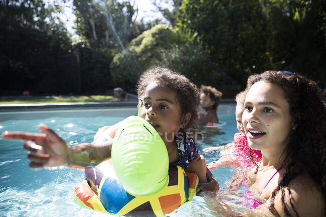 Mother and daughter on inflatable raft playing in sunny swimming pool — Stock Photo