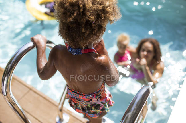 Madre viendo hija entrar en la piscina soleada de verano - foto de stock