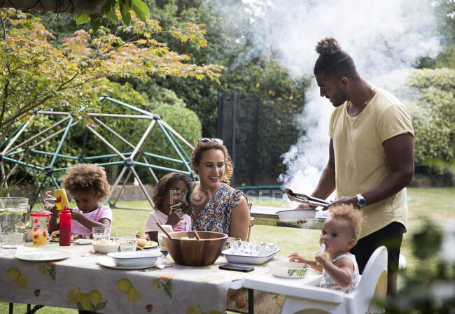 Família feliz desfrutando de churrasco de verão na mesa do pátio — Fotografia de Stock