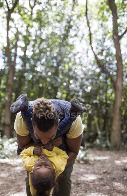 Playful father holding daughter upside down in woods — Stock Photo