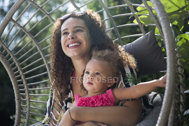 Happy mother holding daughter on sunny patio — Stock Photo