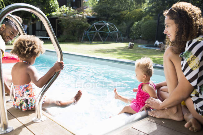 Familia feliz relajarse y chapotear en la soleada piscina de verano - foto de stock