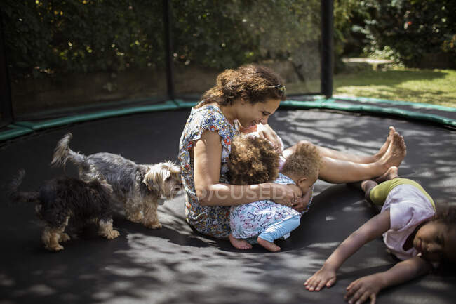 Mother and daughters playing on backyard trampoline with dogs — Stock Photo
