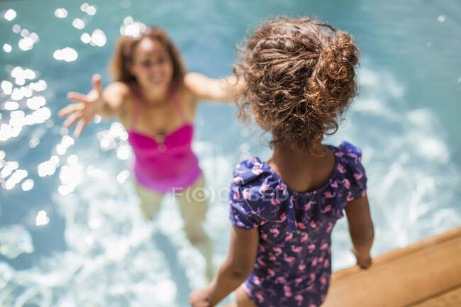 Tochter bereitet Sprung in Arme der Mutter in sonnigem Schwimmbad vor — Stockfoto