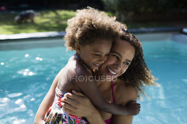 Mère et fille heureuses étreignant au bord de la piscine ensoleillée d'été — Photo de stock