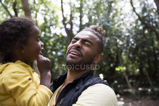 Padre giocoso che tiene la figlia nel bosco — Foto stock