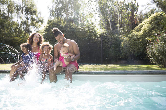 Família brincalhão salpicando na piscina ensolarada de verão — Fotografia de Stock