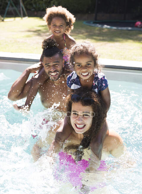 Retrato feliz família espirrando na piscina ensolarada verão — Fotografia de Stock