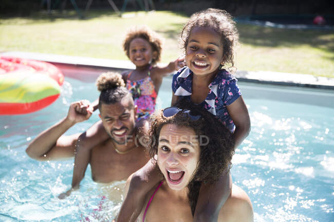 Retrato familiar juguetona en la soleada piscina de verano - foto de stock