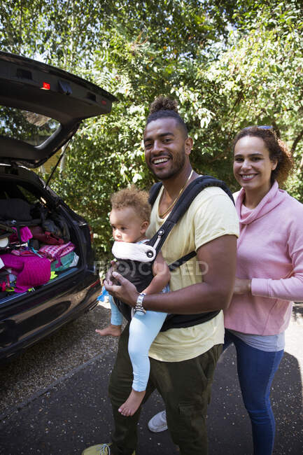 Retrato padres felices con hija pequeña fuera del coche - foto de stock