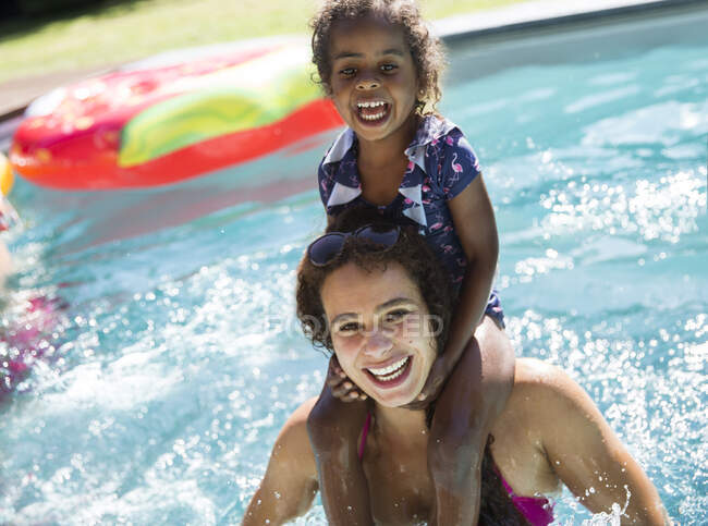 Portrait happy mother carrying daughter on shoulders in swimming pool — Stock Photo