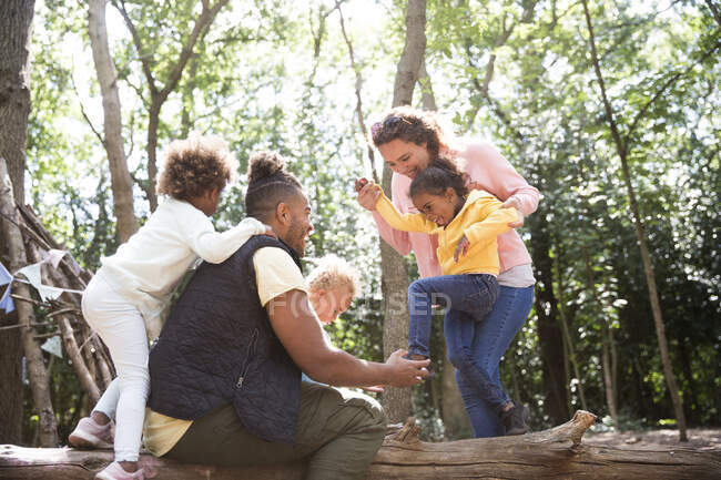Glückliche Familie spielt auf umgestürzten Baumstämmen im Sommerwald — Stockfoto