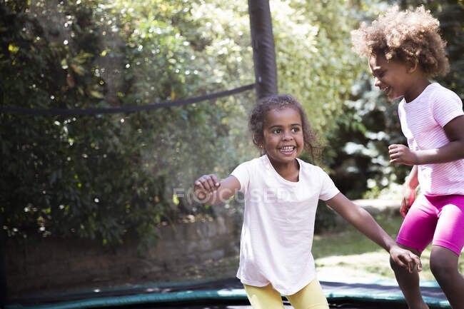 Sorelle felici che saltano sul trampolino del cortile — Foto stock