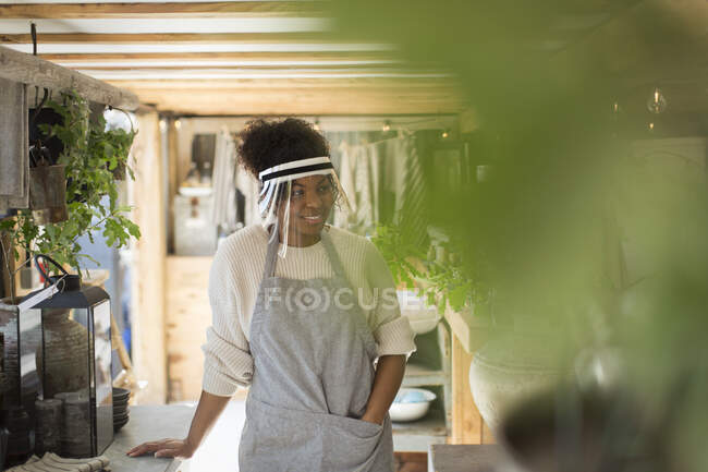 Mujer en protector facial trabajando en vivero de plantas - foto de stock
