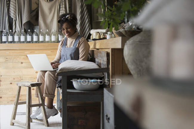 Portrait happy female shop owner using laptop in home goods store — Stock Photo