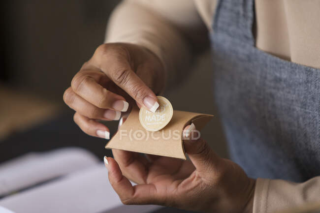 Close up female shop owner placing handmade label on box — Stock Photo