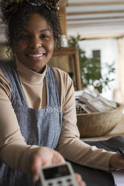 Портрет усміхненої власниці жіночого магазину, що тримає читача кредитних карток — стокове фото