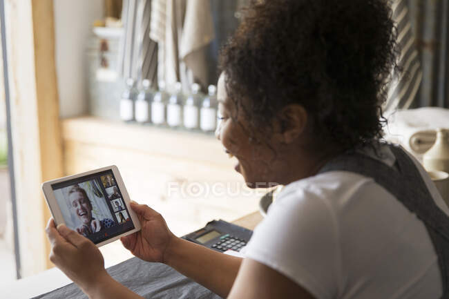 Feminino proprietário da loja de vídeo conversando com amigos no tablet digital — Fotografia de Stock