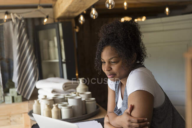 Femme propriétaire de magasin en utilisant un ordinateur portable au comptoir de magasin — Photo de stock