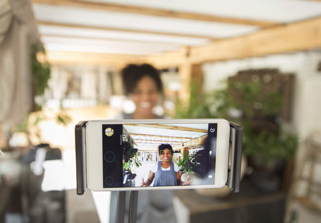 Proprietário da loja fêmea filmando vlog com telefone inteligente no berçário da planta — Fotografia de Stock