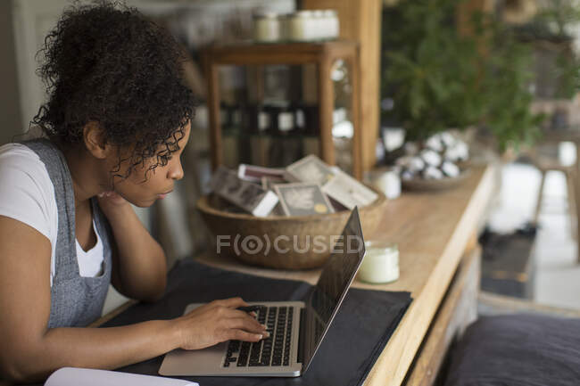 Владелица магазина использует ноутбук на прилавке магазина — стоковое фото