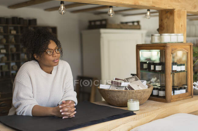 Thoughtful female shop owner behind counter — Stock Photo
