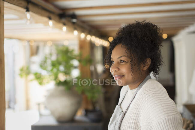 Femme souriante propriétaire de magasin détournant les yeux — Photo de stock