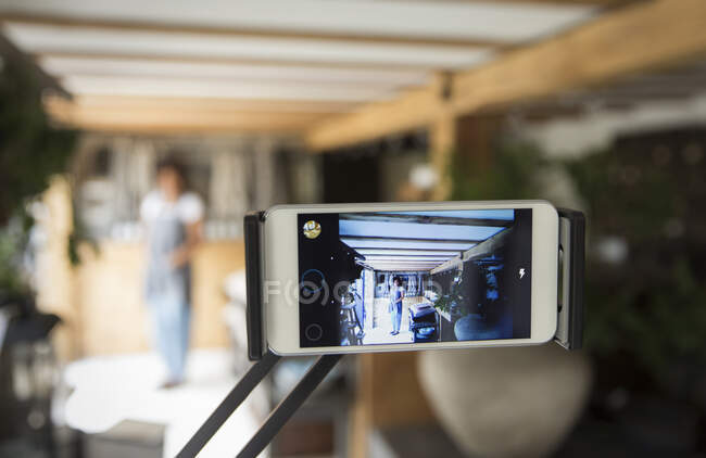 Propietario de negocio de pantalla de teléfono inteligente filmando vlog en vivero de plantas - foto de stock