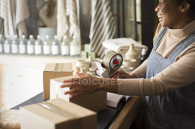 Happy female shop owner taping e-commerce packages — Stock Photo