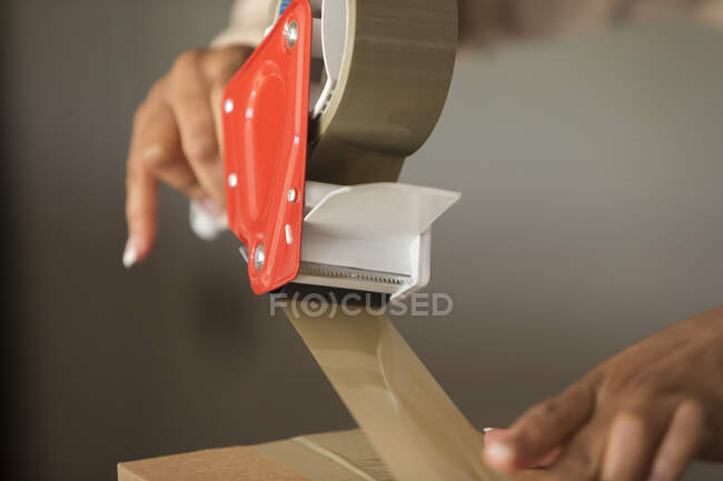 Close up female shop owner taping package for shipping — Stock Photo