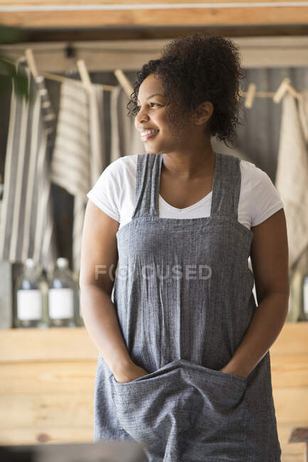 Retrato mujer feliz dueño de la tienda en delantal mirando hacia otro lado - foto de stock