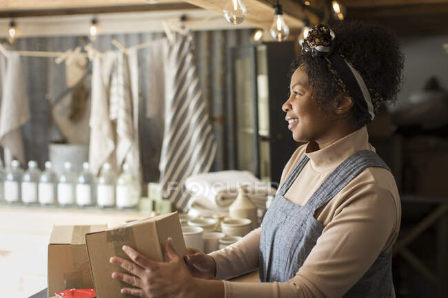 Happy female shop owner with boxes at shop counter — Stock Photo