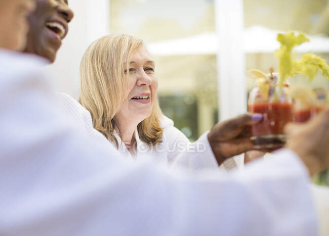 Счастливая пожилая женщина наслаждается кровавым коктейлем Мэри с друзьями — стоковое фото