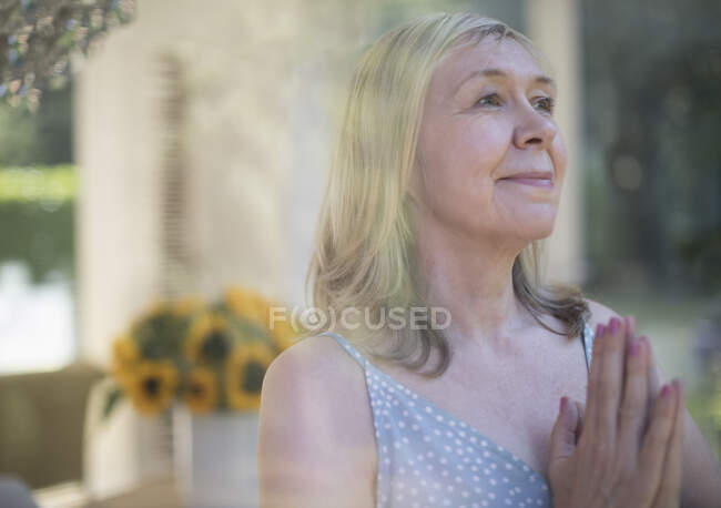 Serena mulher sênior meditando com as mãos apertadas — Fotografia de Stock