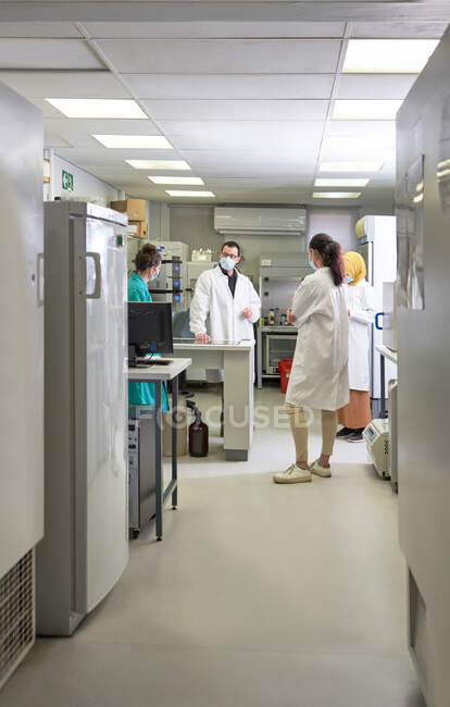 Scientists in face masks meeting in laboratory — Stock Photo