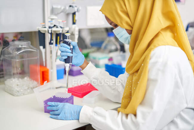 Wissenschaftlerin im Hijab und Gesichtsmaske mit Pipette im Labor — Stockfoto
