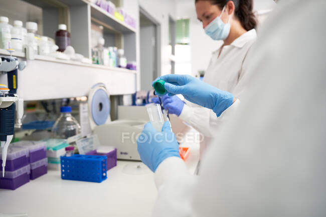 Жіночі вчені в рукавичках і масці обличчя працюють в лабораторії. — стокове фото