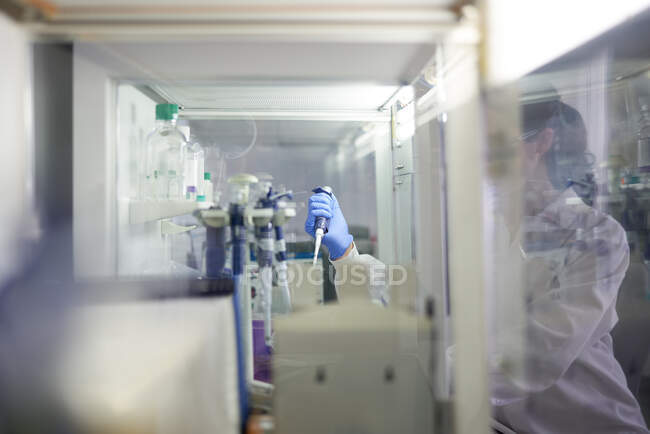 Wissenschaftlerin mit Pipette an Dunstabzugshaube im Labor — Stockfoto
