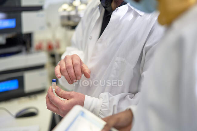 Primo piano scienziati esaminando flaconcino in laboratorio — Foto stock