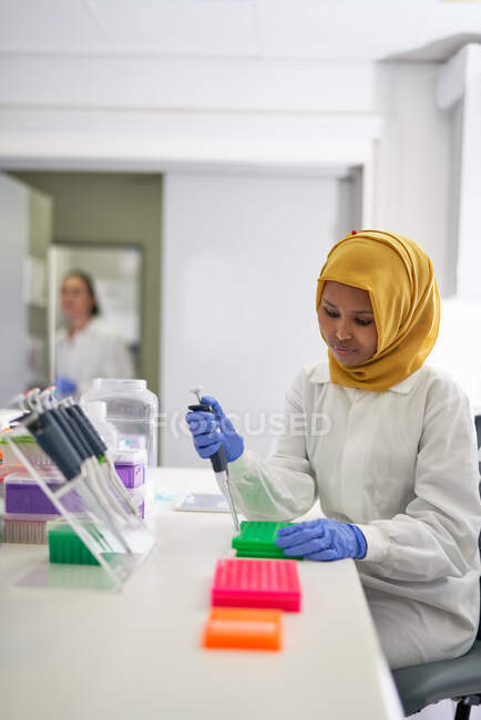 Wissenschaftlerin im Hijab füllt Pipettenschalen im Labor — Stockfoto
