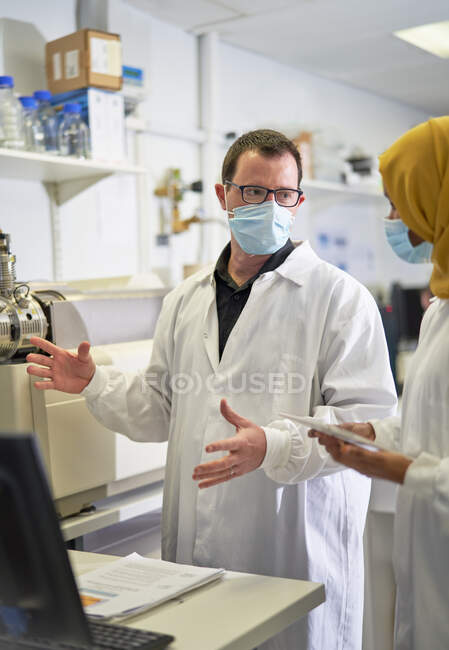 Wissenschaftler mit Gesichtsmasken reden im Labor — Stockfoto