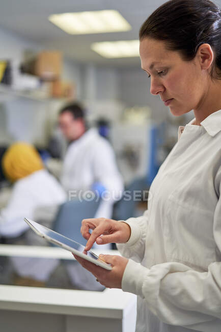 Femme scientifique à l’aide de tablette numérique en laboratoire — Photo de stock