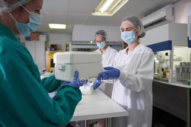 Científicas femeninas con enfriador de muestras en laboratorio - foto de stock